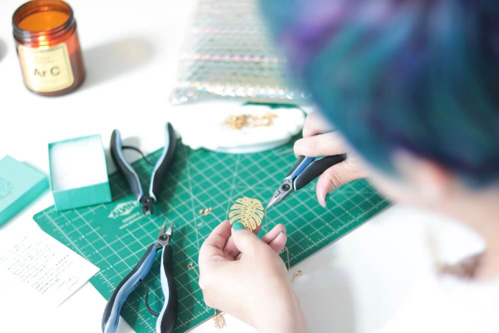 A Tea Leaf gold monstera jewelry pieces being made