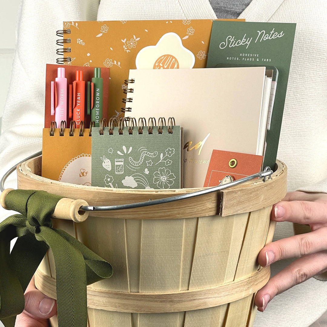 Wooden basket filled with stationery items held by a person