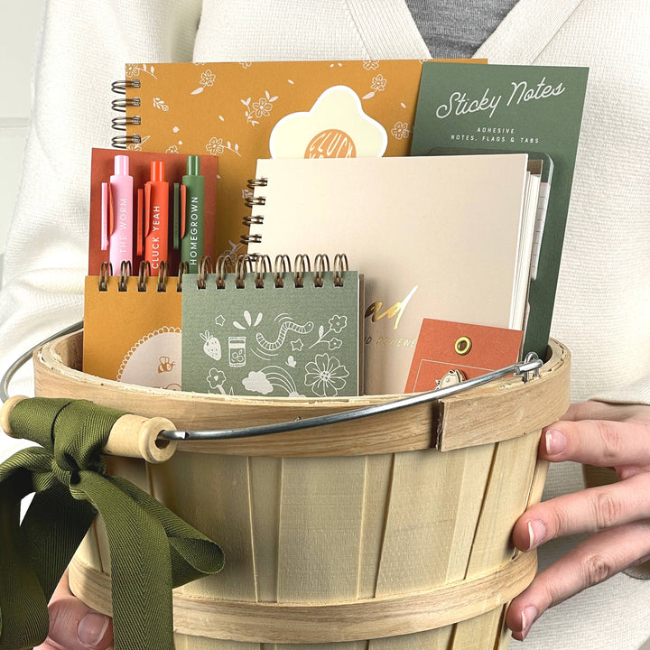 Wooden basket filled with stationery items held by a person