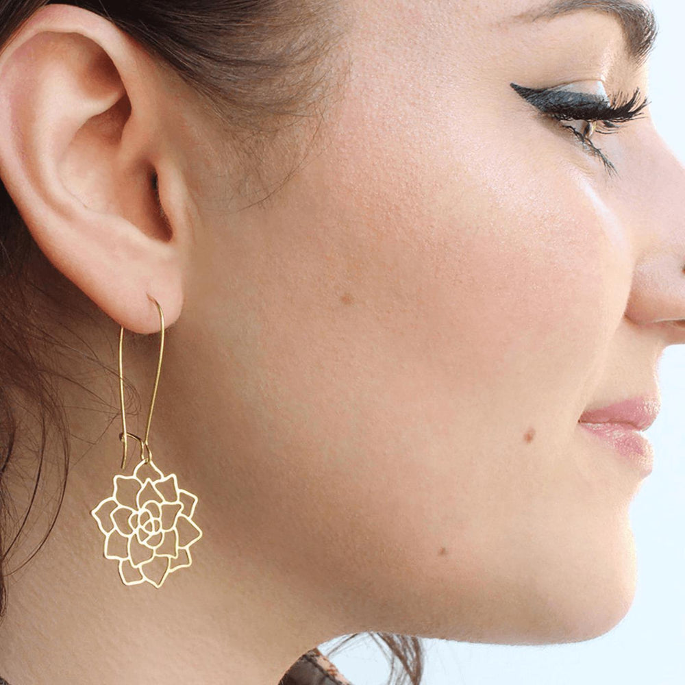 A women's face turns to the side as she wears elegant gold succulent rosette earrings