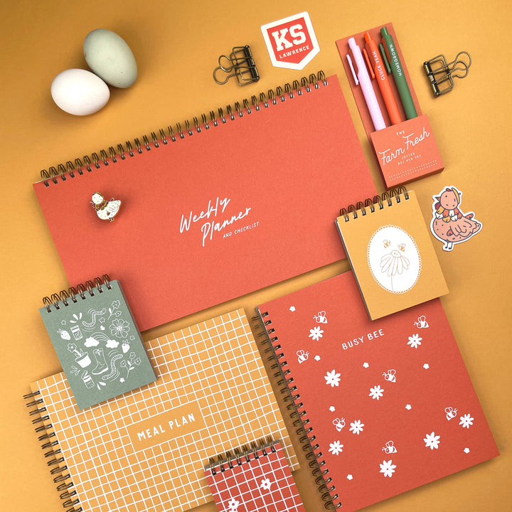 Collection of spiral-bound planners and stationery items on a yellow background