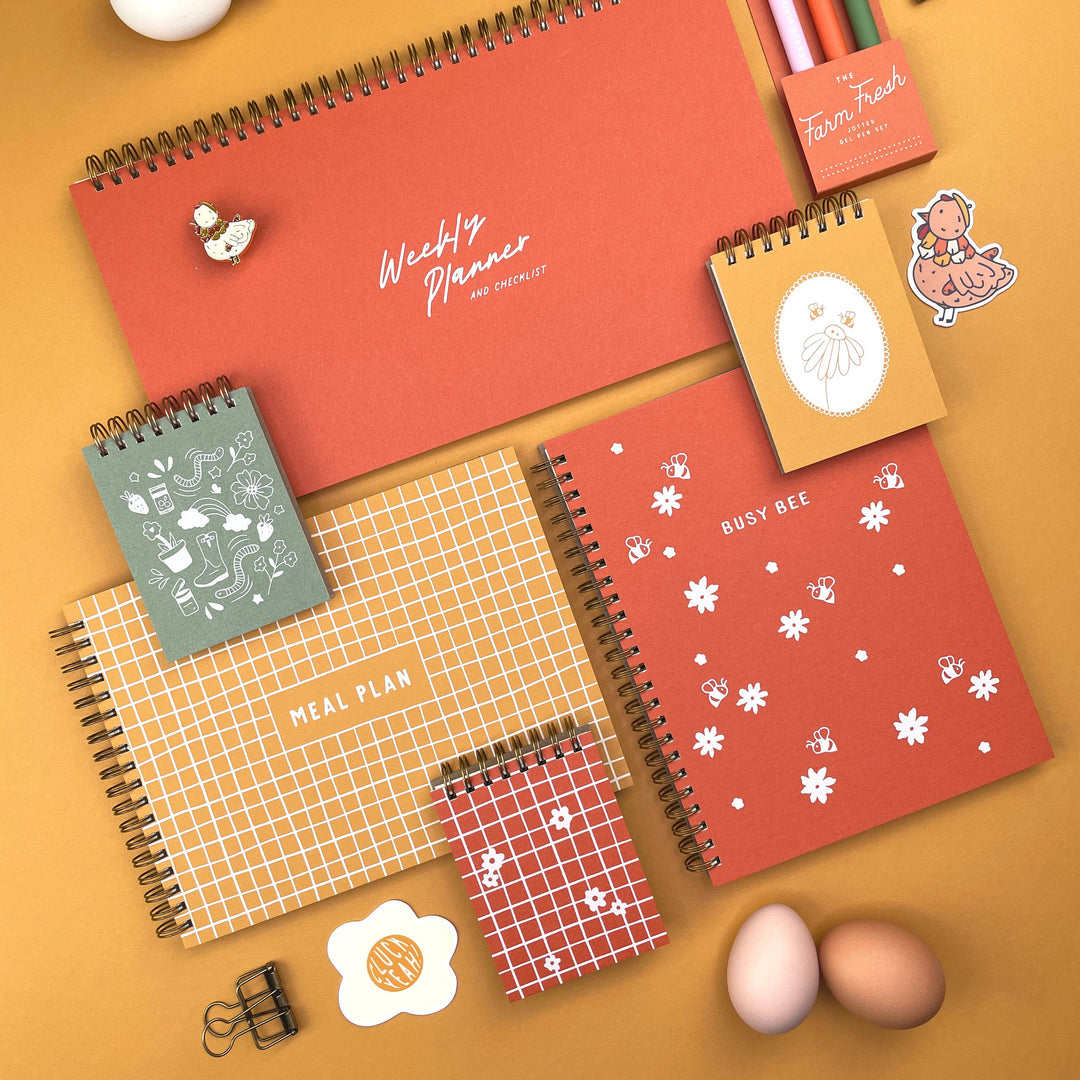 Collection of spiral-bound planners and stationery items on a yellow background